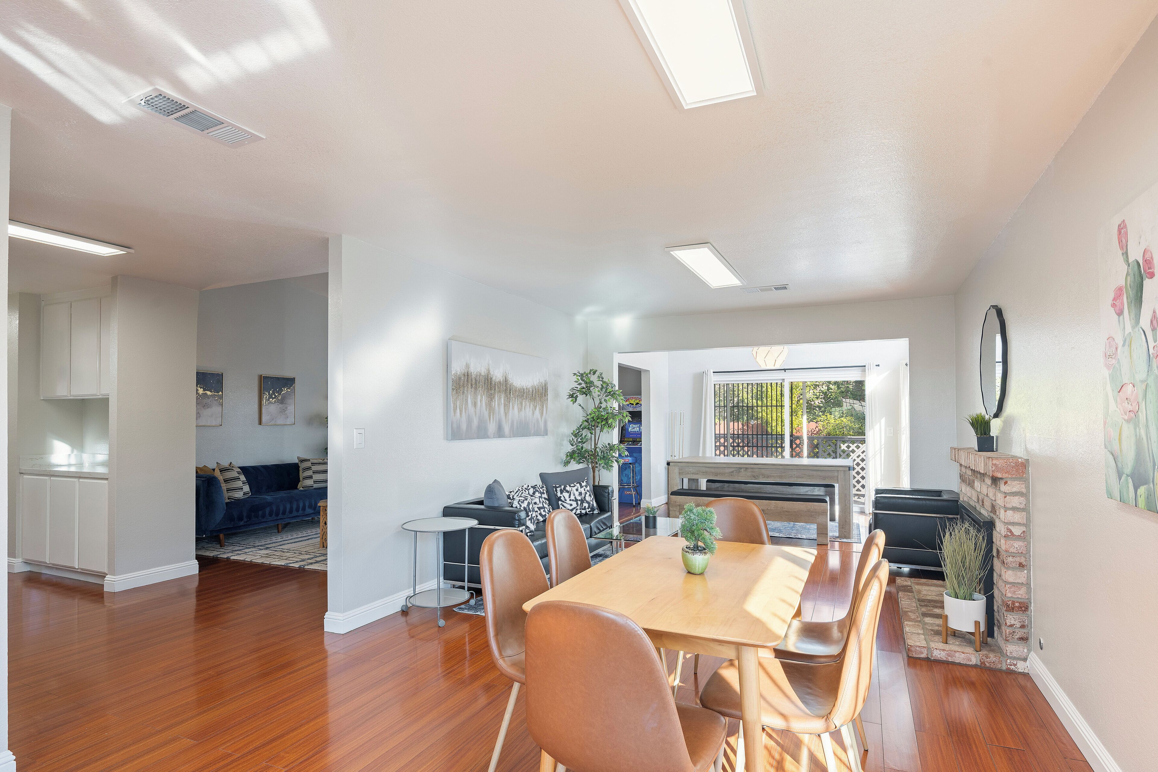 A spacious living area with a wooden dining table, comfortable seating, a fireplace, and a view of the outdoors.