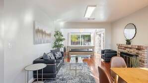 Een moderne woonkamer met een bank, salontafel en open haard.