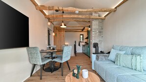 A cozy interior with a wooden ceiling, a dining area with chairs and a table, a sofa, and a kitchen area. - 1 bedroom beautiful home in Remetinec (Remetinec)