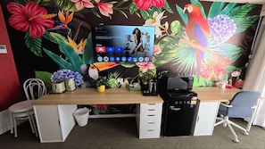 A room with a wooden desk, a computer monitor, a trash bin, and a black printer. - Cozy Ocean View Hotel Room丨Sleeps 4丨2 Double-Bed (Surfers Paradise)