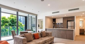 Eine moderne Wohnung mit Wohnbereich, Küche und großen Schiebeglasfenstern zum Balkon.