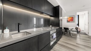 A modern kitchen with dark cabinetry, stainless steel appliances, and a sleek countertop.
