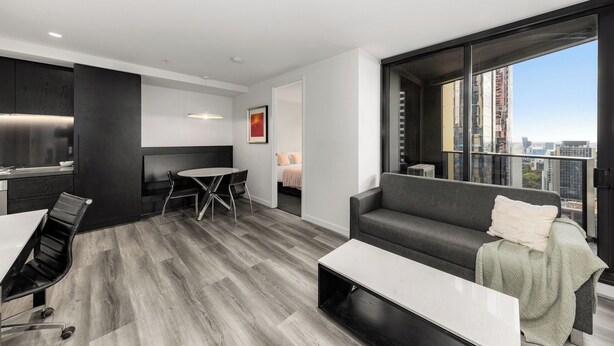 A modern apartment with a dining area, a sofa, and a large window with a city view.
