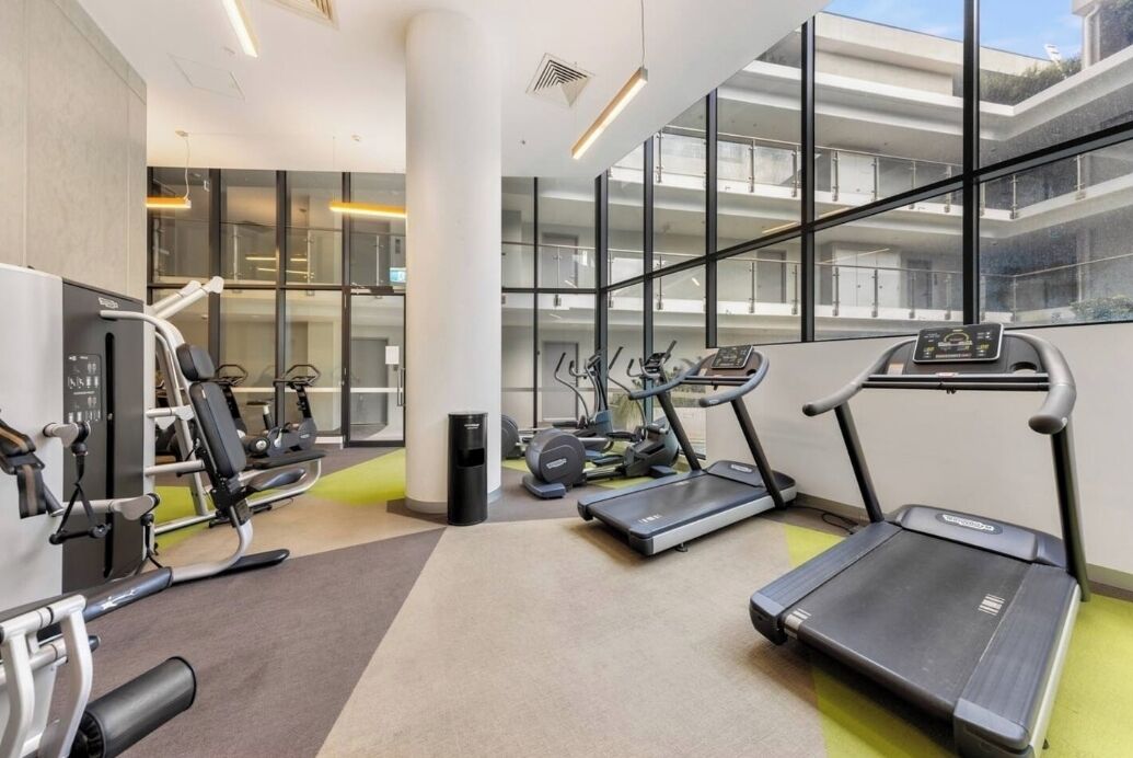 A modern gym with treadmills, elliptical machines, and weight equipment.