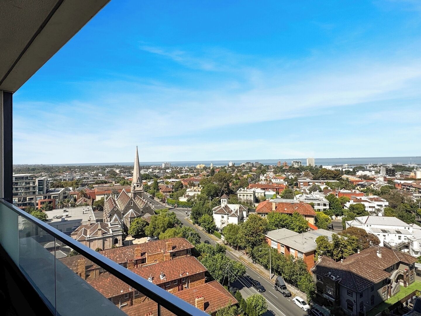Eine Stadtansicht mit einem markanten Kirchturm, Wohnhäusern und blauem Himmel.