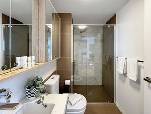 Bathroom features a large mirror, a vanity, and a glass shower enclosure.