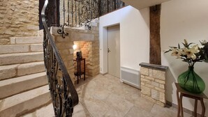 A staircase with a wrought iron railing, a stone wall, a small table with a lamp, and a vase with flowers on the floor. - 7 bedroom beautiful home in Flaignes-Havys (Flaignes-Havys)