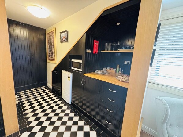 A compact kitchen with black cabinets, a microwave, and a small refrigerator. - Leura's Magical Manderley - Studio Room (Leura)