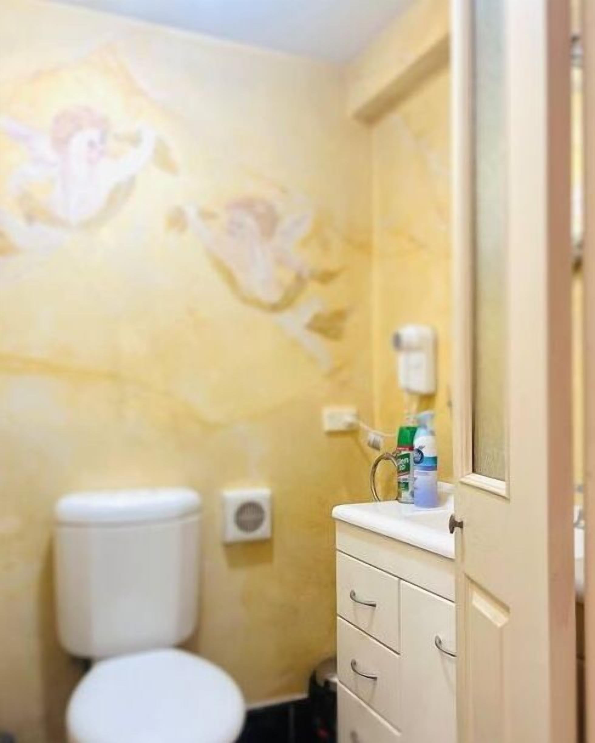 Ein kleines Badezimmer mit Toilette, Waschbecken mit Spiegel und einem Wandseifenspender.