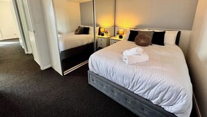 A hotel room with a large bed, a wardrobe, a bedside table with lamps, and a mirror. - Central Parramatta 2BR | Steps from Train and Shops (Parramatta)