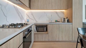 A modern kitchen with a built-in oven, a gas stove, and a microwave.