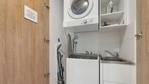 A compact laundry room with a washing machine, dryer, and ironing station.