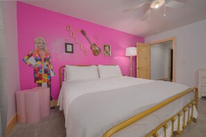 Une chambre avec un lit, un mur rose, une guitare et un miroir.