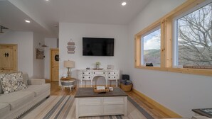 A living room with a sofa, a coffee table, a TV, and a fireplace.