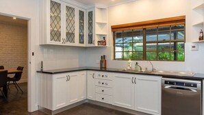 A kitchen with white cabinetry, a built-in dishwasher, and a window with a view of greenery.