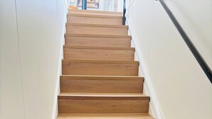 Un escalier en bois, avec des murs blancs et une rampe noire.