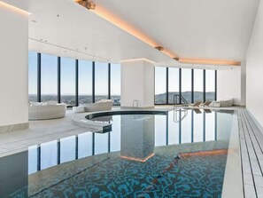 Ein moderner, überdachter Pool mit freiem Blick auf die Stadt durch große Fenster.