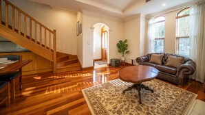 Ein geräumiges Wohnzimmer mit einer Holztreppe, einem Ledersofa, einem Couchtisch und einem großen Teppich.