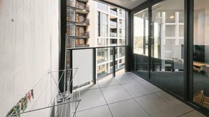 Un appartement moderne doté d’un balcon, de grandes fenêtres et offrant une vue sur d’autres immeubles.