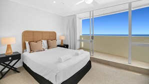 A hotel room with a bed, two bedside tables with lamps, a ceiling fan, and a large window with a view of the ocean. - Breathtaking Ocean view 3Bedrooms Unit next Beach (Surfers Paradise)
