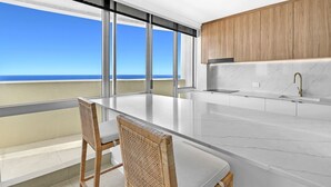 A modern kitchen with a large island, wooden cabinets, and a view of the ocean. - Breathtaking Ocean view 3Bedrooms Unit next Beach (Surfers Paradise)
