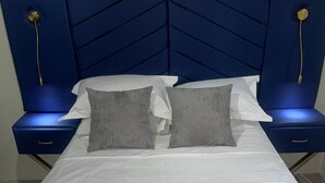 A neatly made bed with white linens and two gray pillows, flanked by two bedside tables with lamps.