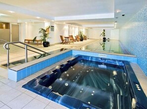 Ein Wellnessbereich mit Whirlpool, Sitzgelegenheit und Glasgeländer.