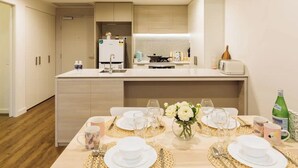 Une cuisine moderne dotée d’un îlot central, d’un coin repas aménagé pour quatre personnes et d’un petit réfrigérateur.
