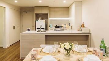 A modern kitchen with a central island, a dining area set for four, and a small refrigerator.