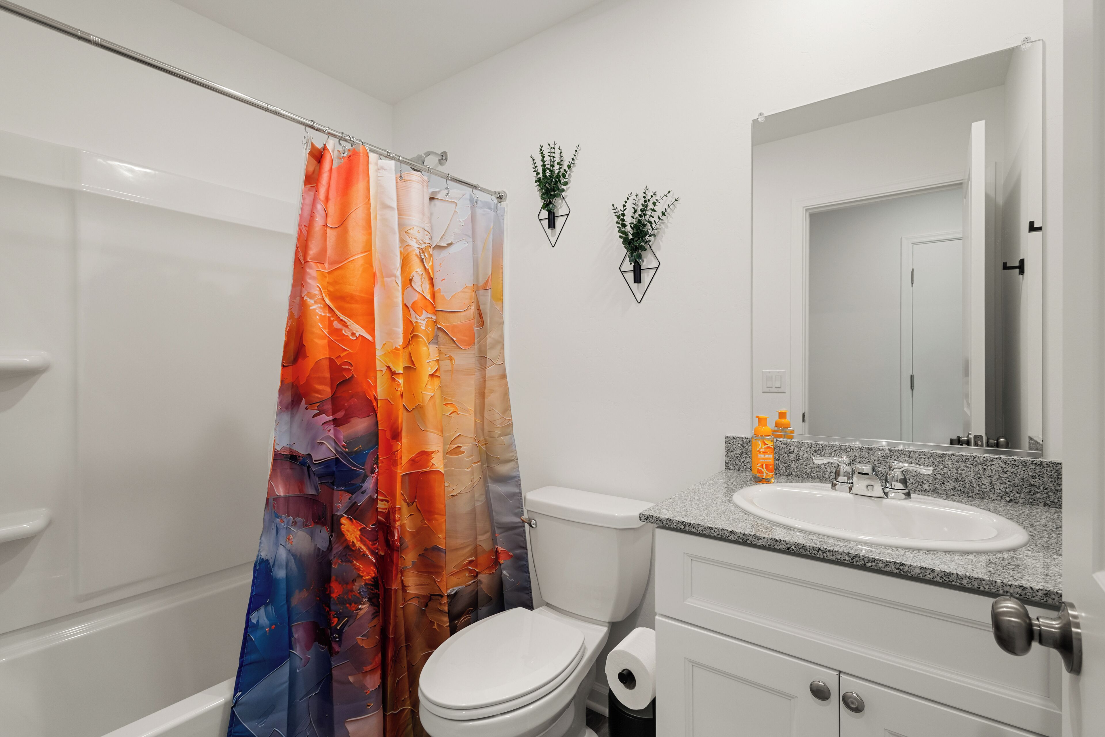 Un baño con cortina de ducha, inodoro, lavabo y espejo.
