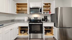 Eine moderne Küche mit weißen Schränken, einer Edelstahl-Mikrowelle, einem Backofen und einem Kühlschrank.