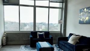A spacious living room with a large window, a ceiling fan, and a blue sofa. - Cozy 1-bedroom apartment in beautiful downtown Atlanta with amazing view  (Atlanta)