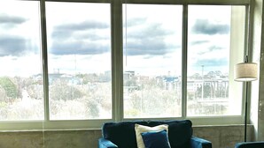 A living room with a large window, a blue sofa set, and a patterned rug. - Cozy 1-bedroom apartment in beautiful downtown Atlanta with amazing view  (Atlanta)