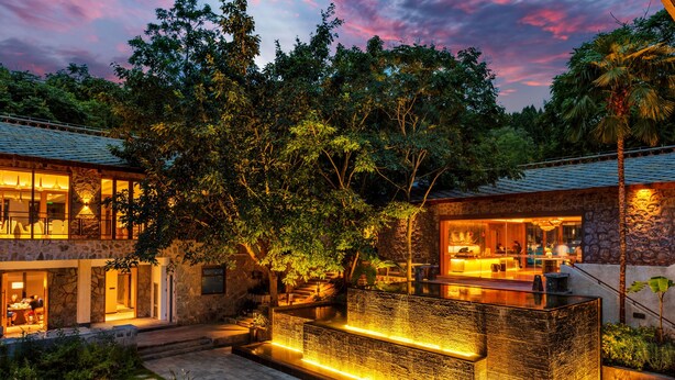 A modern house with a stone exterior, a swimming pool, and a well-lit outdoor area. - YAOJIA WATERFALL VILLAGE RESORT (Anshun)