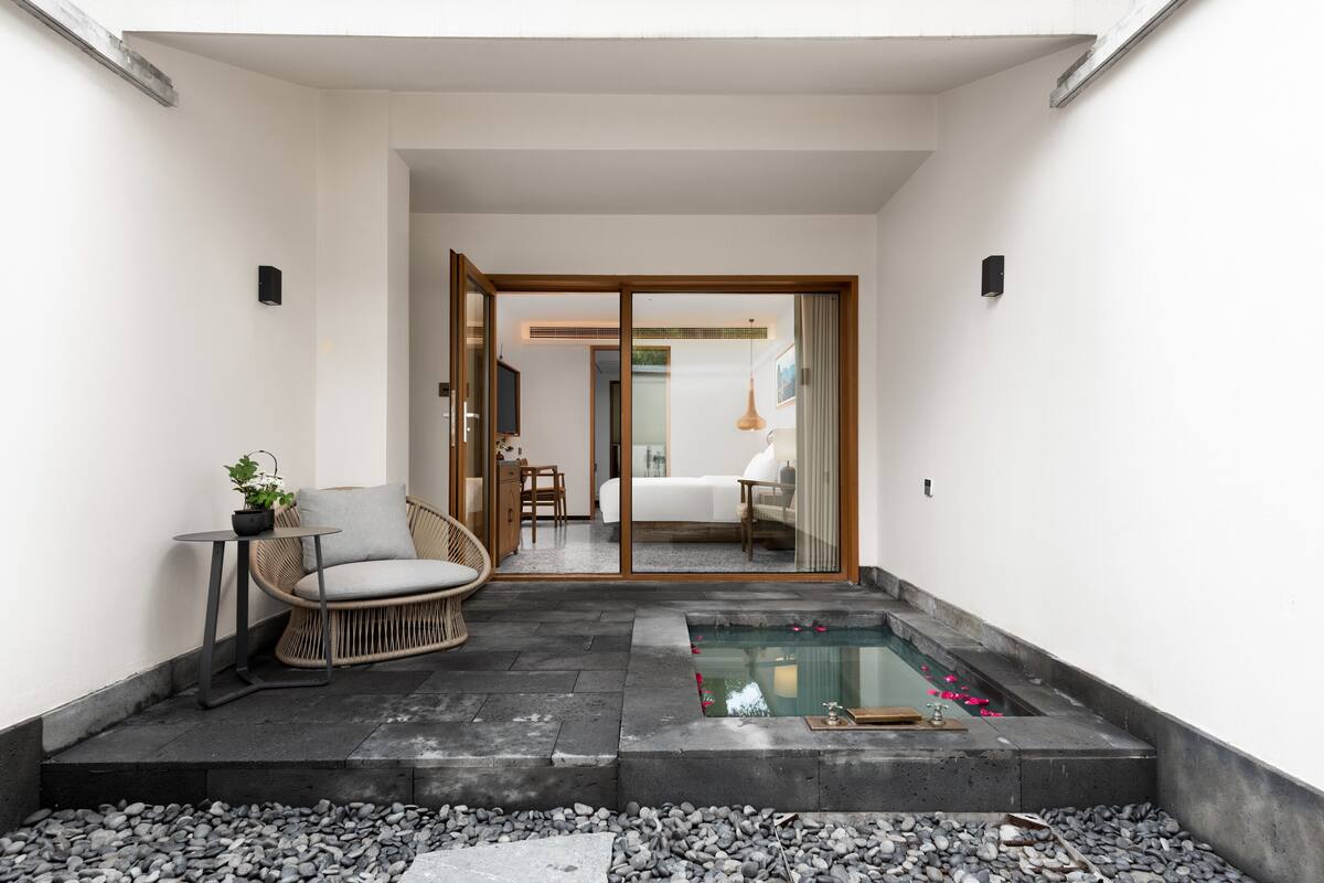 Ein moderner Außenbereich mit Sitzgelegenheit, einem kleinen Pool und einem Weg zu einem Zimmer mit Bett und Badezimmer.