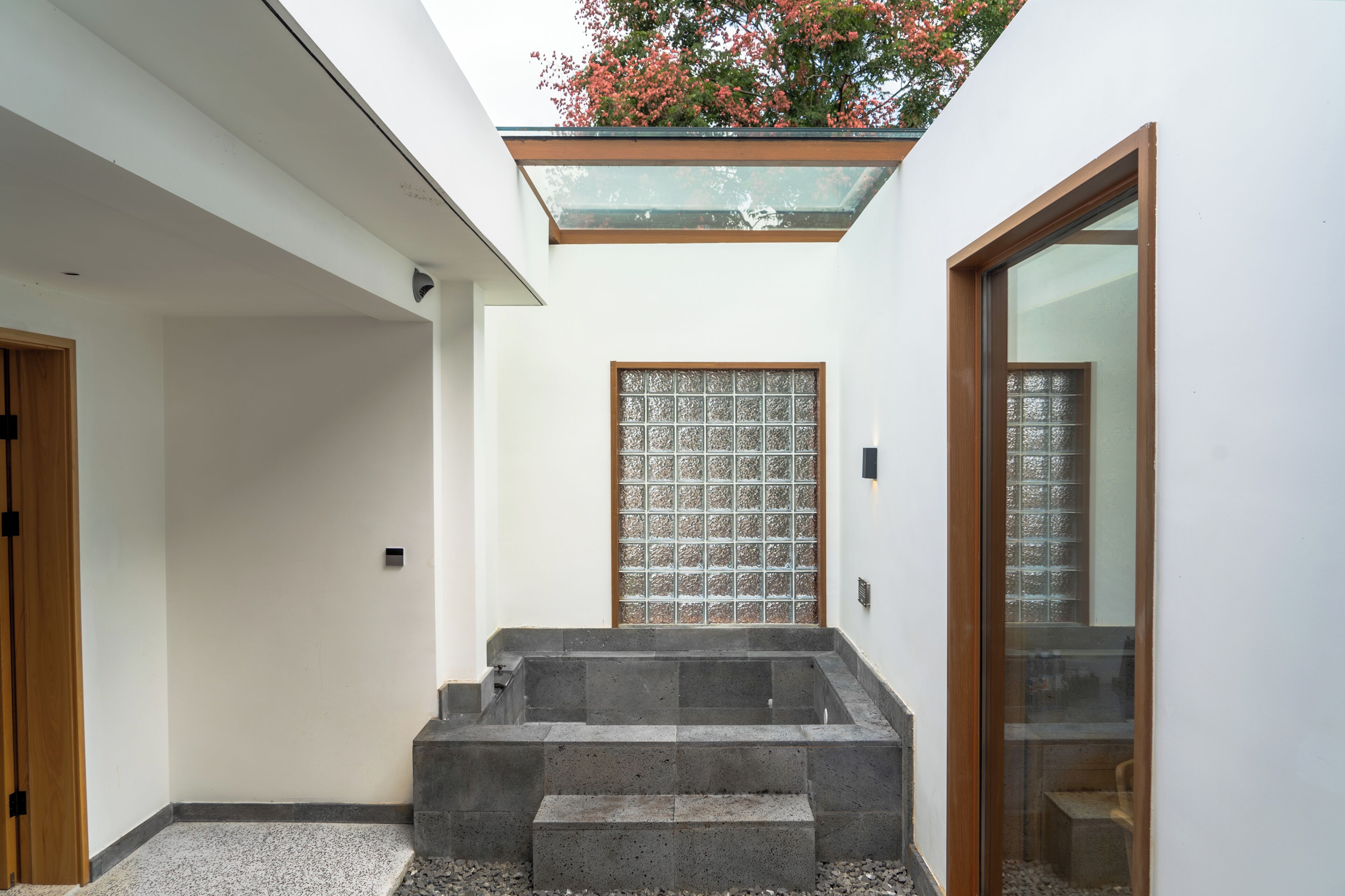 Un intérieur moderne avec un escalier en pierre, une porte en verre et une porte en bois.