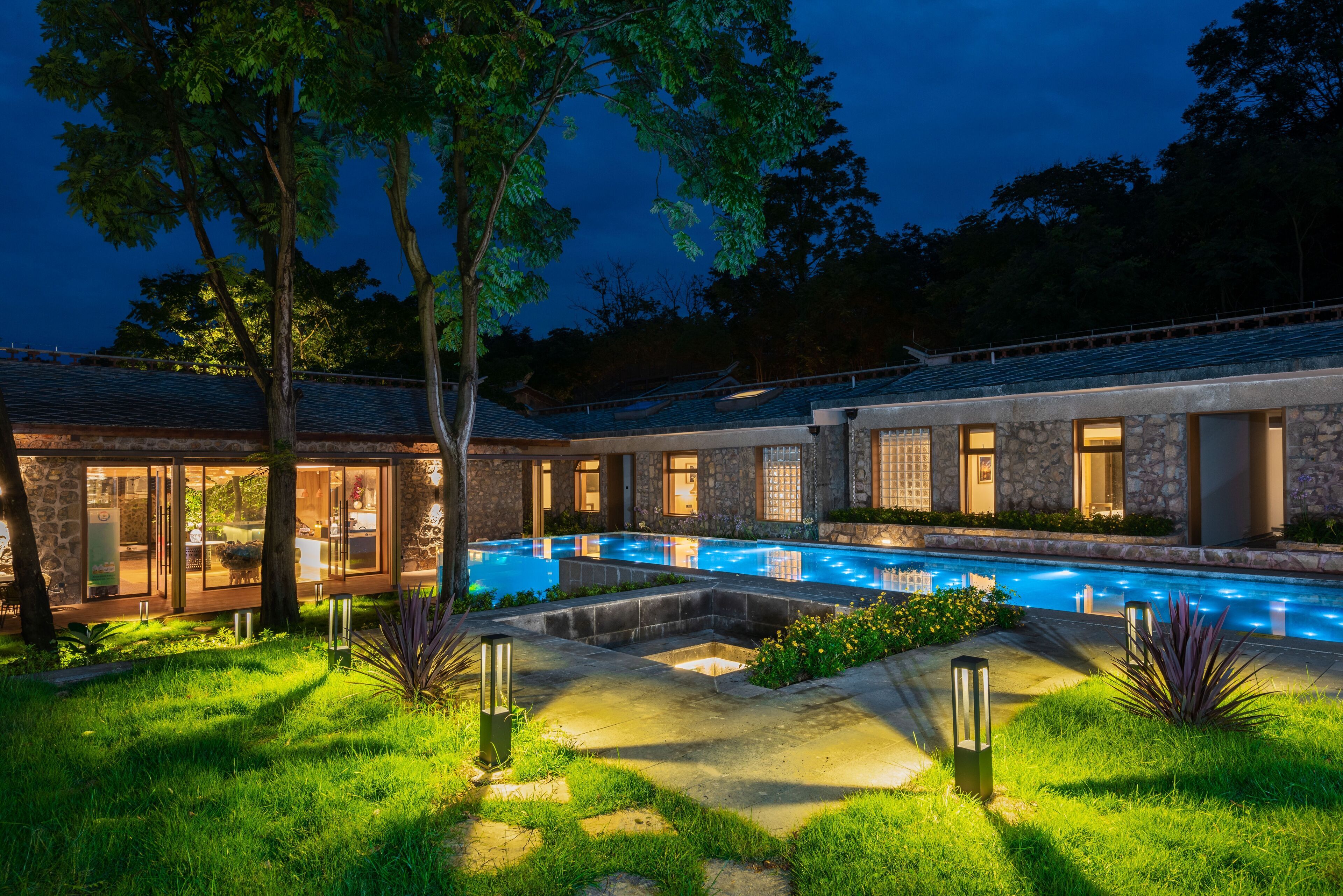Una casa moderna con piscina, fachada de piedra y puertas de cristal.