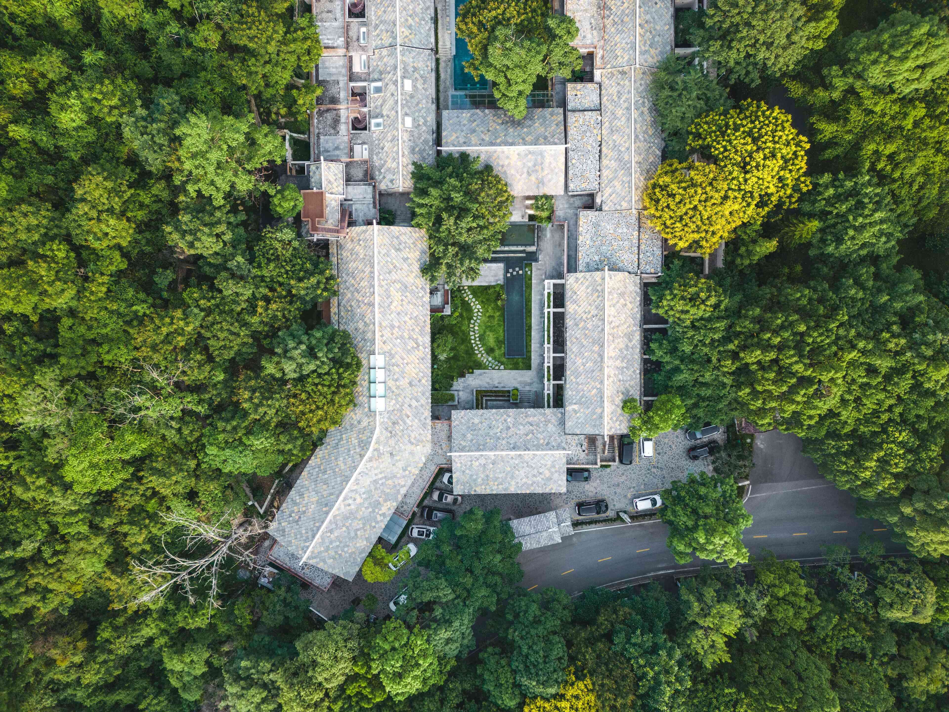 Vista aérea de un edificio moderno con varias secciones, rodeado de abundante vegetación.