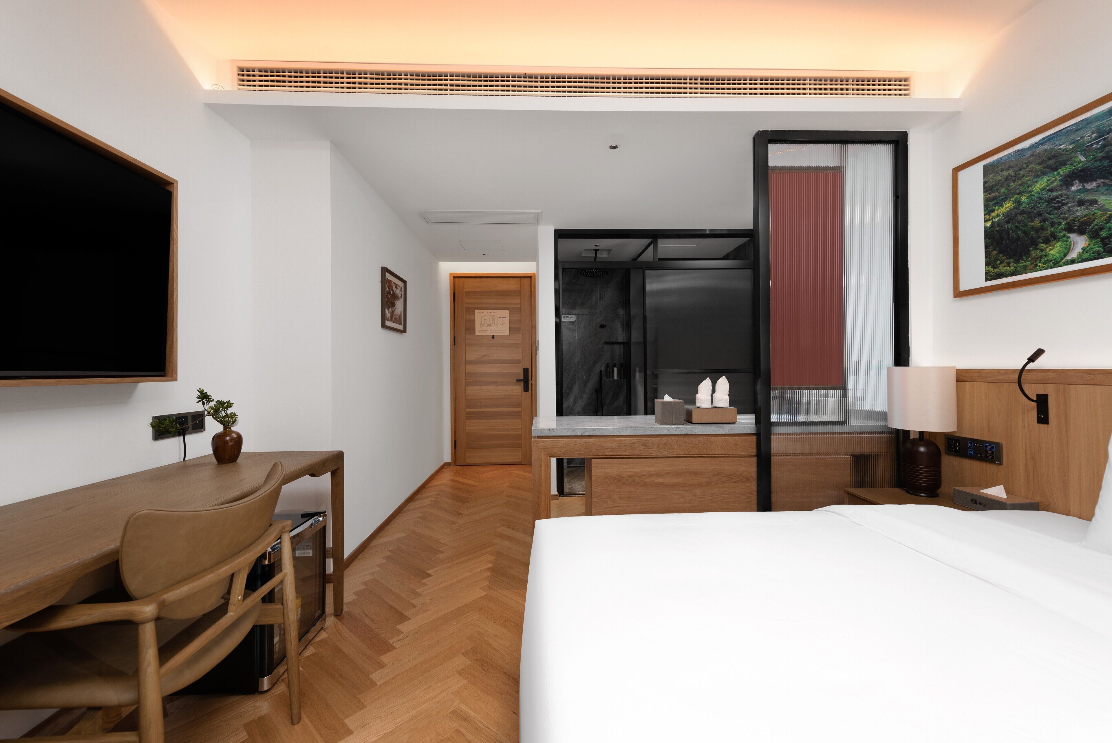 Habitación de hotel con cama, escritorio, silla y zona de ducha.