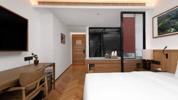 Habitación de hotel con cama, escritorio, silla y zona de ducha.
