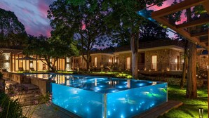 A rectangular swimming pool with clear water, surrounded by stone steps and lush greenery. - YAOJIA WATERFALL VILLAGE RESORT (Anshun)