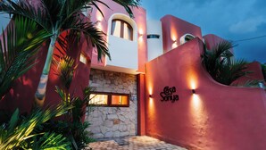 Un edificio moderno con una facciata rosa, un ingresso in pietra e un'insegna che recita "Casa Sonya".
