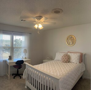 Relax in this serene bedroom with a comfortable bed, ceiling fan, and desk area.