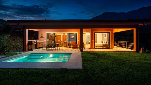 Una casa moderna con piscina, patio y zona de cocina.