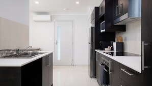 A modern kitchen with dark cabinetry, a white countertop, and stainless steel appliances.