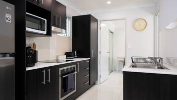 A modern kitchen with dark cabinetry, a microwave, a coffee maker, and a sink.
