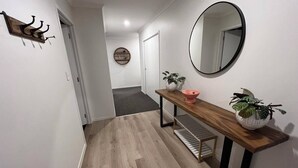 A hallway with a wooden bench, a round mirror, and a potted plant.