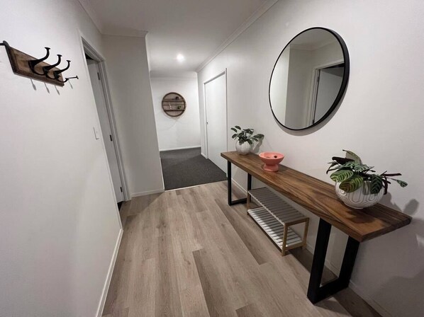 Un pasillo con un banco de madera, un espejo redondo y una planta en maceta.