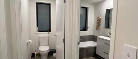 Un baño moderno con inodoro, lavabo y zona de ducha.