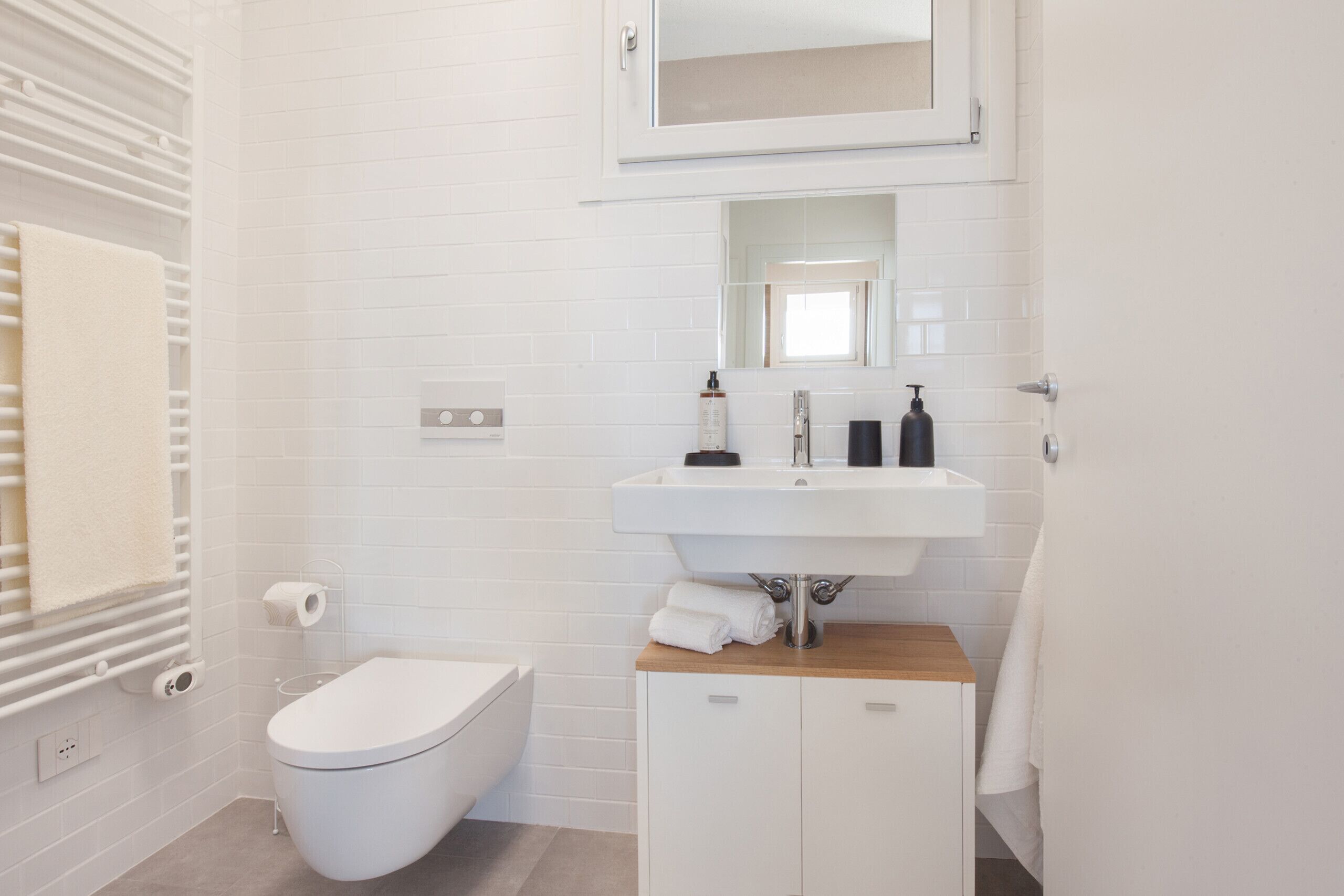 A modern bathroom with a white toilet, a sink with a mirror above it, and a towel rack.